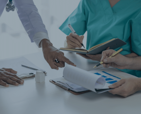 Healthcare professionals discussing nursing staff recruitment strategies over documents and charts, representing recruitment agencies' role in healthcare.