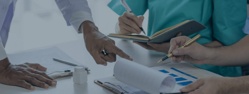 Healthcare professionals discussing nursing staff recruitment strategies over documents and charts, representing recruitment agencies' role in healthcare.