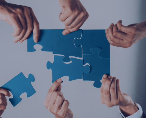 Hands assembling puzzle pieces, symbolizing the integration of recruitment agencies into internal hiring processes for smooth collaboration.